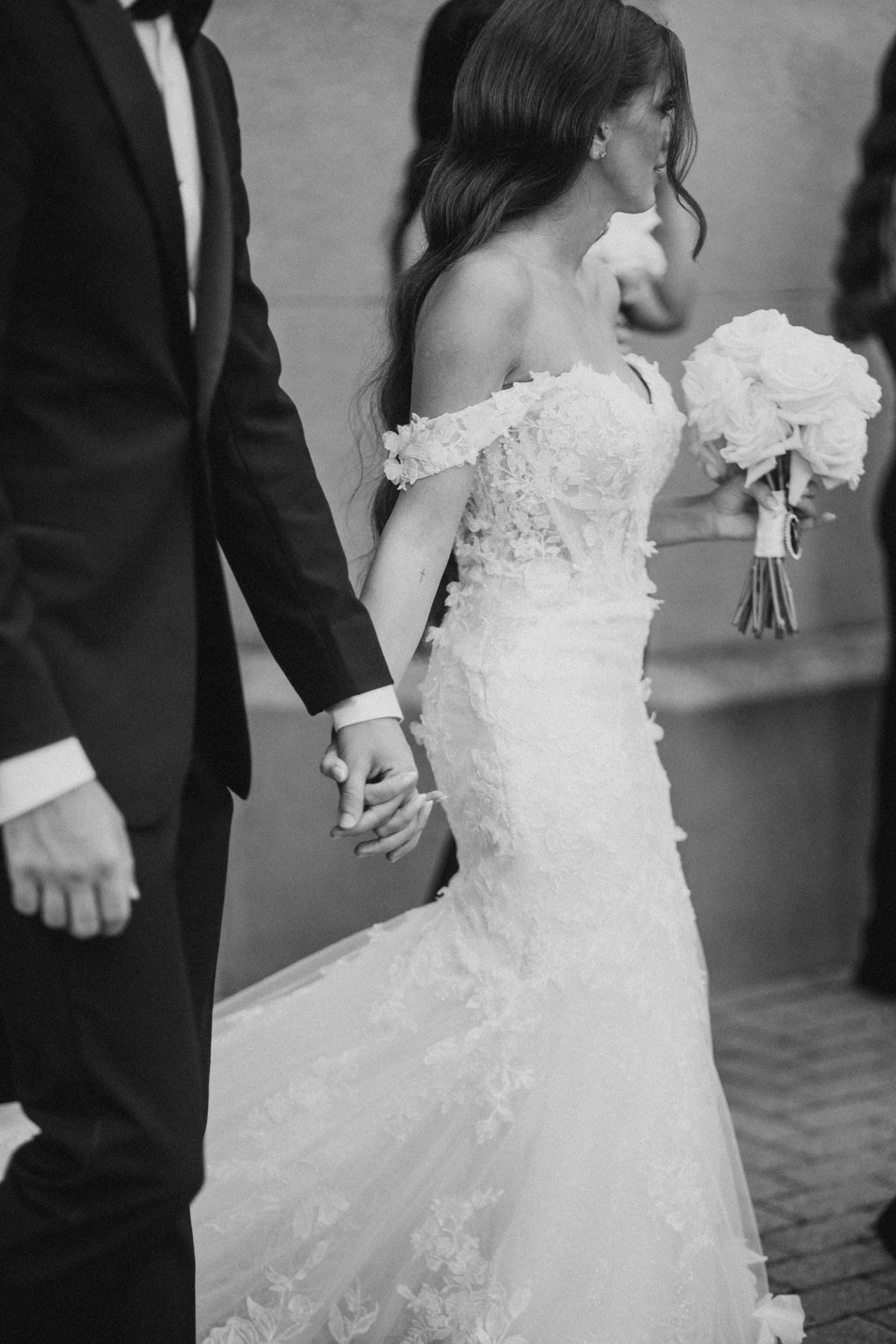 Bride and groom walking hand in hand in black and white