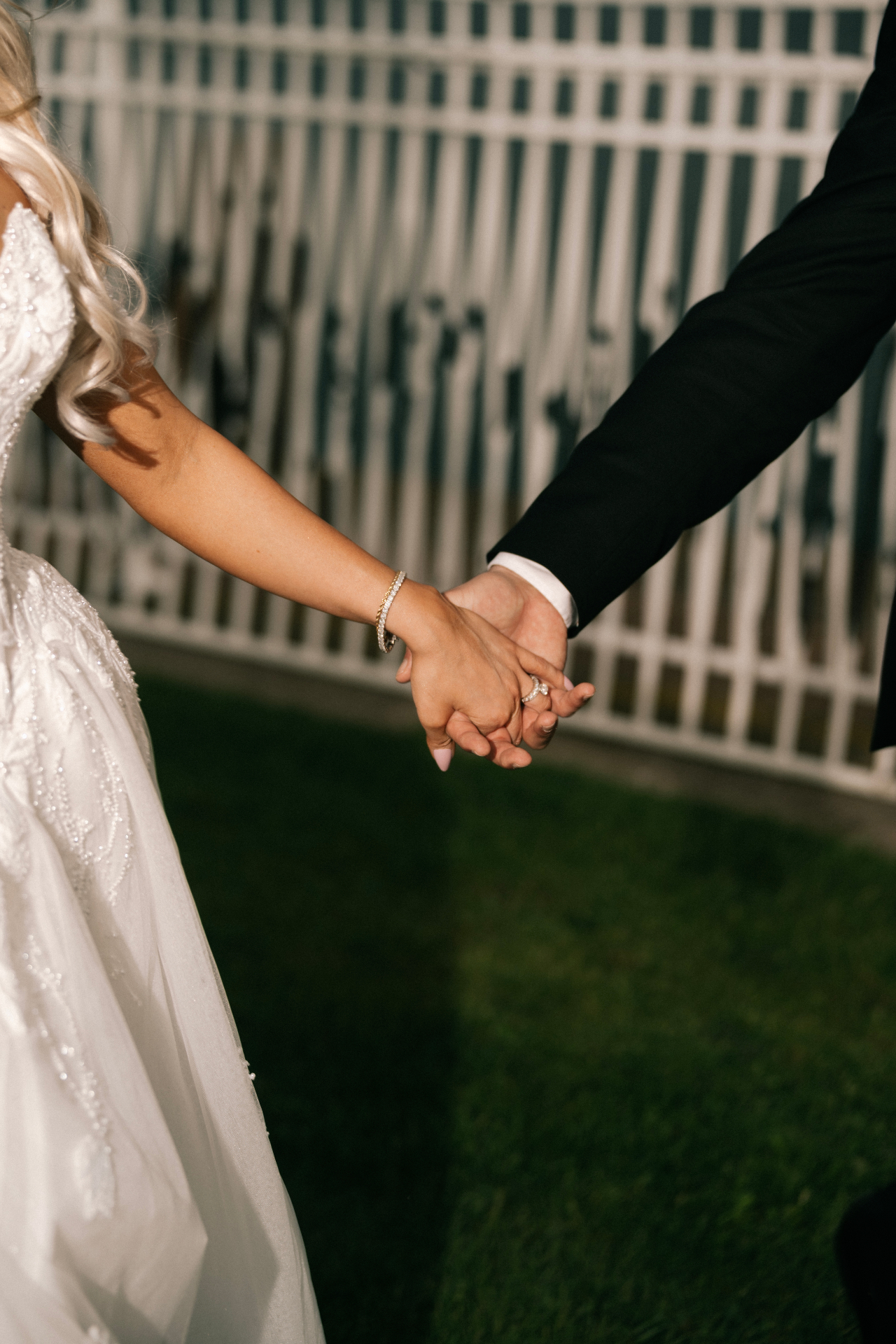 Bride and groom walking hand in hand at dusk