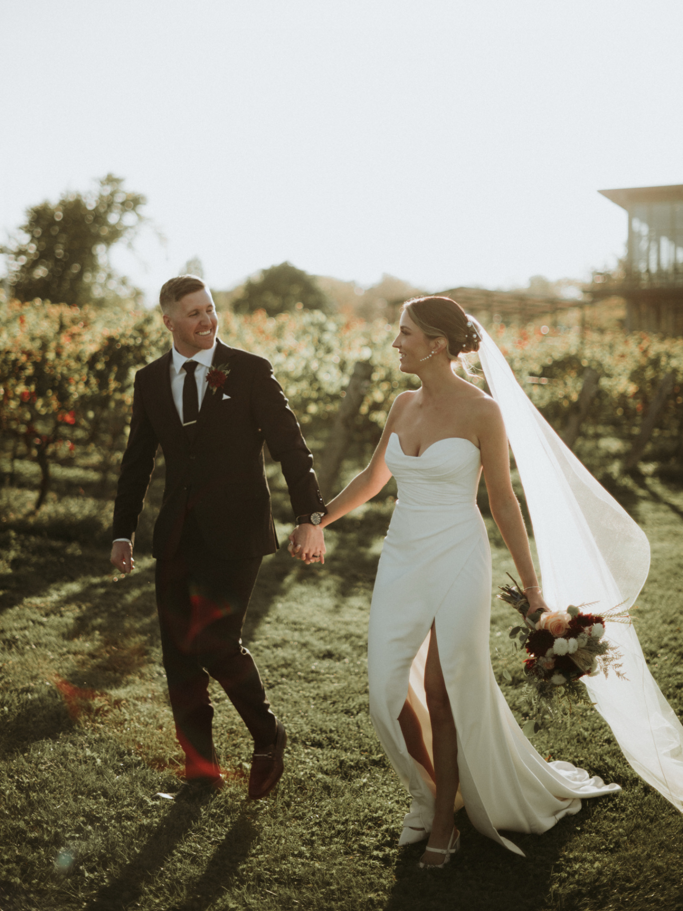 Bride and groom walking through the vineyard at sunset