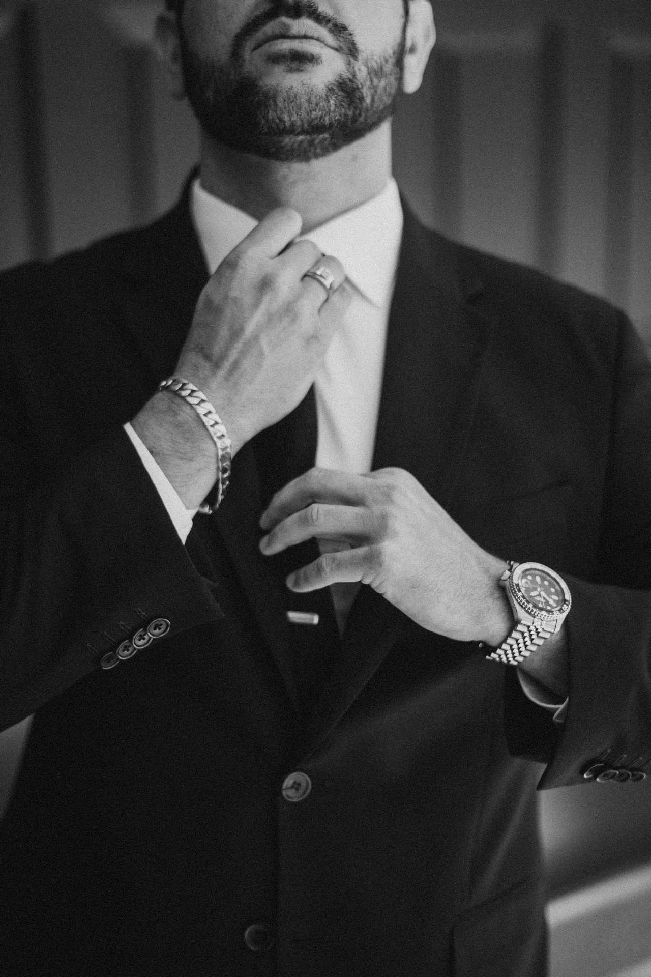 Groom adjusting his tie in black and white